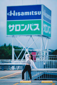 Full length of woman standing against sign