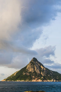 Scenic view of sea by mountain against sky