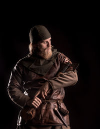 Serious viking with axe standing against black background