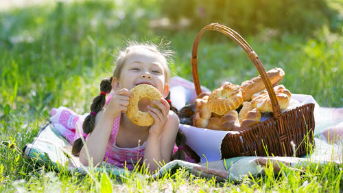 Portrait of girl having bagel while lying at park