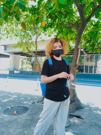 Woman standing by swimming pool against trees