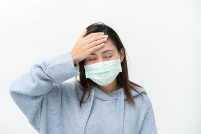 Portrait of woman covering face against white background