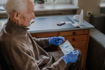 Senior man holding surgical mask at home