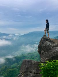 Silhouette of woman standing on mountain against cloudy sky