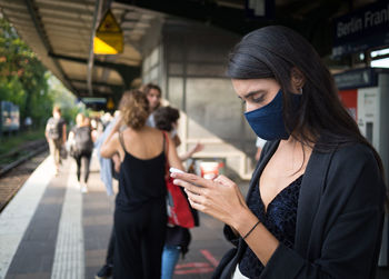 Young woman using mobile phone at railroad station