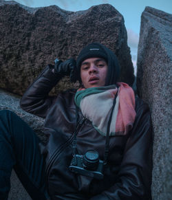 Portrait of man sitting by rock formations