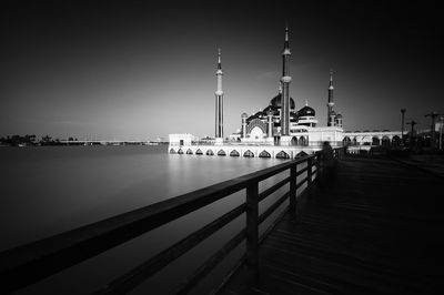 View of illuminated building by river against sky