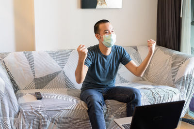 Young man sitting on sofa at home