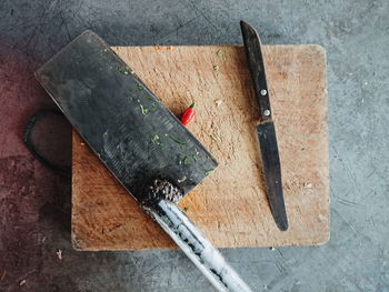 Directly above shot of knife and meat cleaver on cutting board over table