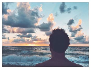 Rear view of man on beach against sky during sunset