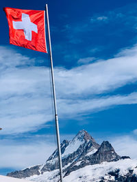 Low angle view of flag on snowcapped mountain against sky