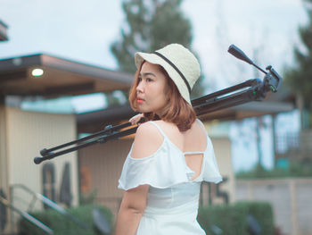 Young woman in hat standing against blurred background