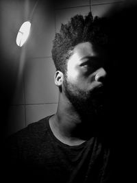 Portrait of young man looking away against wall