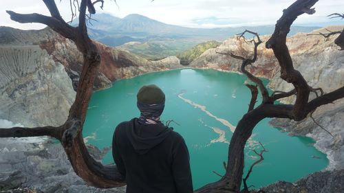 Rear view of man looking at lake against mountain at ijen crater, situbondo.