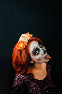 Portrait of woman wearing mask against black background