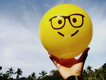 Midsection of person holding balloons against sky