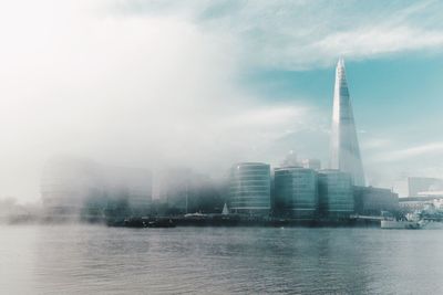 City at waterfront against cloudy sky