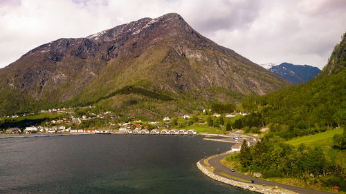 Scenic view of river by mountains against sky