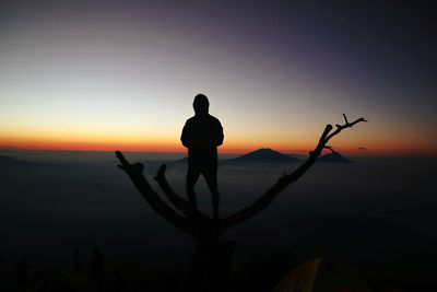 Silhouette man standing on shore against sky during sunset