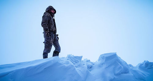 Low angle view of man on snow against clear sky