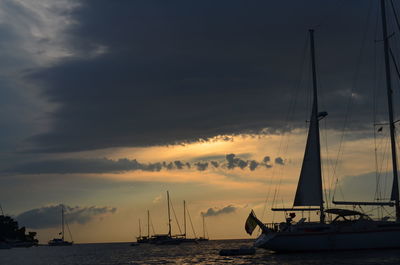 Ships in sea against cloudy sky during sunset