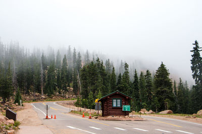 Log cabin on country road against trees in foggy weather