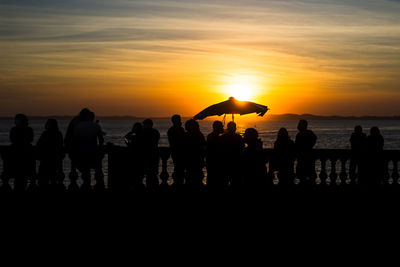 Silhouette of people enjoying the wonderful colorful sunset of farol da barra in salvador, bahia.