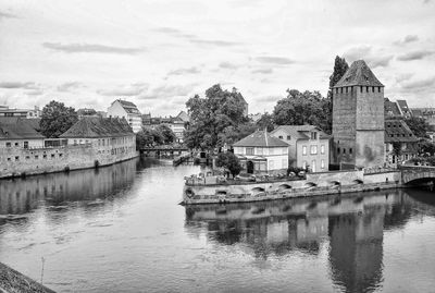 Buildings by river against sky in city