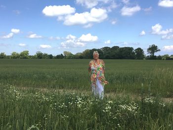 Woman standing on grassy field against sky