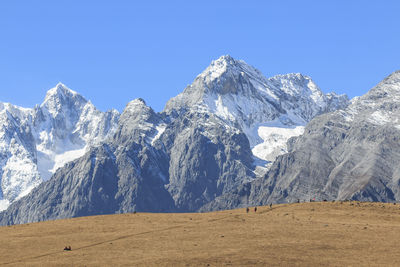 Low angle view of snowcapped mountain against clear blue sky