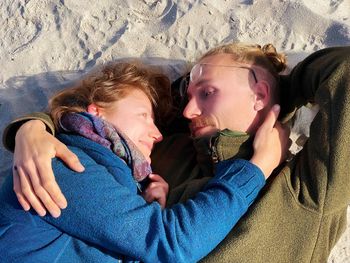 Side view of young couple lying at beach