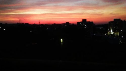 Silhouette buildings in city against sky at sunset