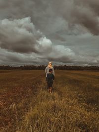 Rear view of man standing on field against sky