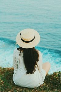 Rear view of woman sitting by sea