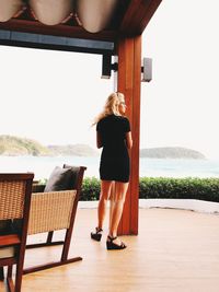 Rear view of woman standing on chair