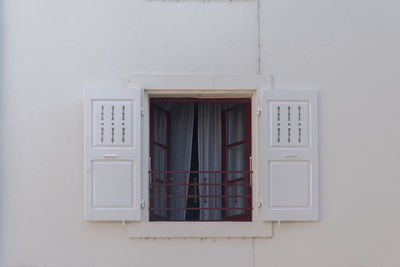 An open window with grey curtains. low angle view of window on building 