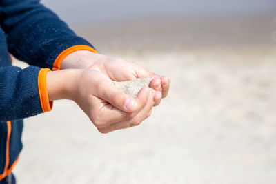 Midsection of child holding sands on beach