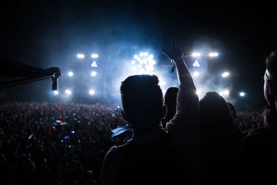 Rear view man gesturing towards crowd during music concert