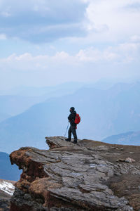 Side view of mid adult man standing on mountain against cloudy sky