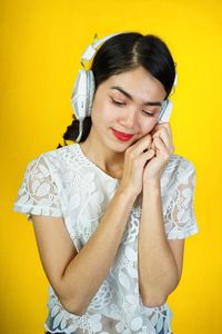Portrait of a smiling young woman against yellow background