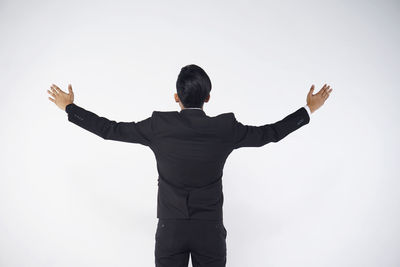 Rear view of man with arms outstretched against white background