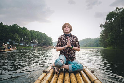 Portrait of young woman standing by lake