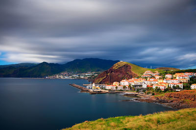 Scenic view of sea by buildings against sky