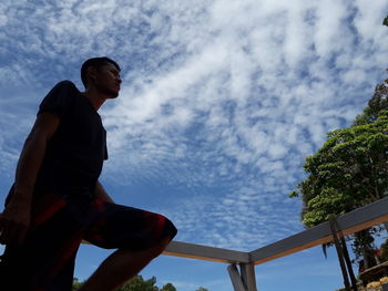Low angle view of man sitting against sky