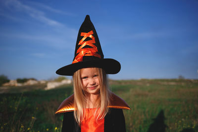 Portrait of smiling girl standing on field against sky