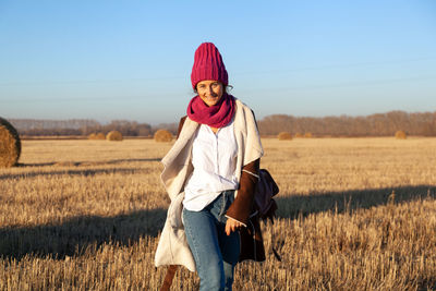 Fashion lifestyle portrait of young trendy woman dressed in brown sheepskin coat and knitting hat 