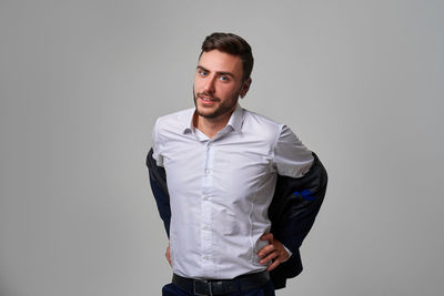 Portrait of young man standing against gray background