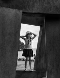 Full length portrait of woman standing against wall