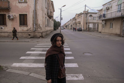 Portrait of young woman standing on road in city