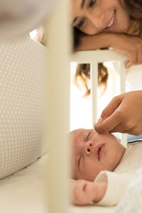 Mother touching toddler son sleeping in crib at home